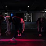 4 Frauen führen gleichzeitig eine Yoga übung aus noch vorne gebeugt