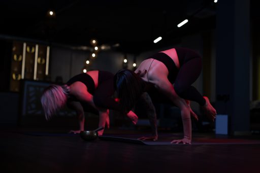 Yoga Übung die krähe ausgeführt von 2 Frauen gleichzeitig