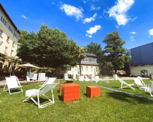 Aussenbereich der cantina majolika mit rasen und vielen liegestühlen unter blauen himmel